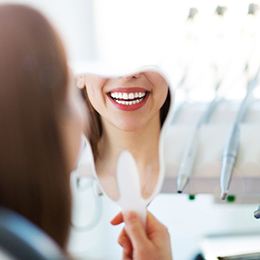patient seeing their new smile in a mirror in dental office