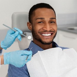 Man smiling next to dentist holding dental tools