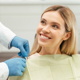 Patient smiling while dentist puts bib in place