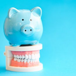 Blue piggy bank standing on top of a dental model