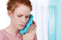 A woman holding an ice pack to her cheek