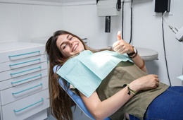 Woman smiling with thumb up in dental chair