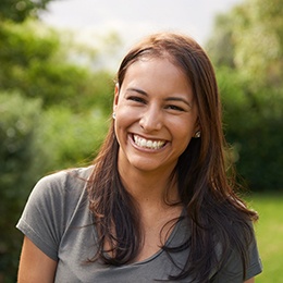 Woman in grey shirt standing outside and smiling