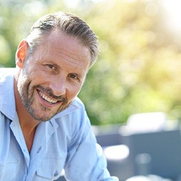 Older man sitting outside and smiling