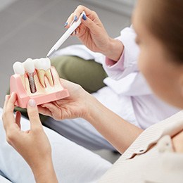 a patient holding a model of dental implants in Concord, NH