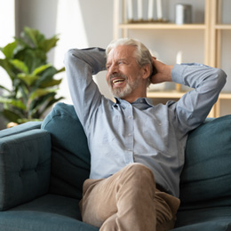 Senior man sitting on couch relaxing and smiling