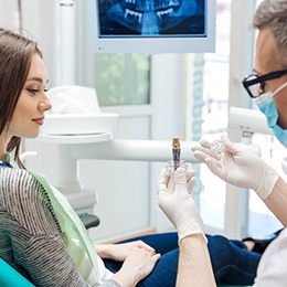 dentist showing a dental implant to a patient