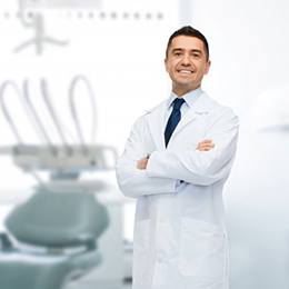 A male dentist smiling with his arms crossed