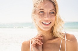 Young female on beach smiling after teeth whitening 