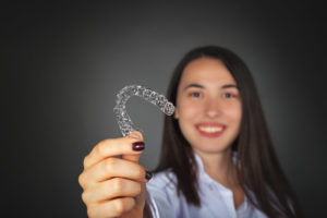 woman holding clear Invisalign tray