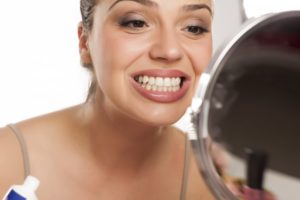 woman looking in the mirror for signs of teeth shifting 