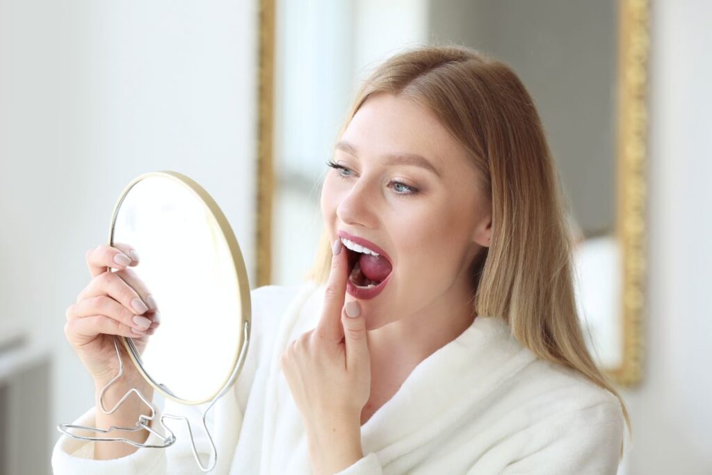 A woman looking in the mirror at her teeth.