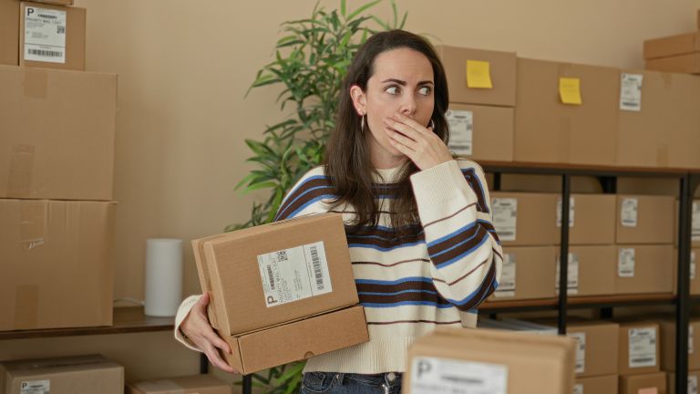 A woman covering her mouth and holding a package